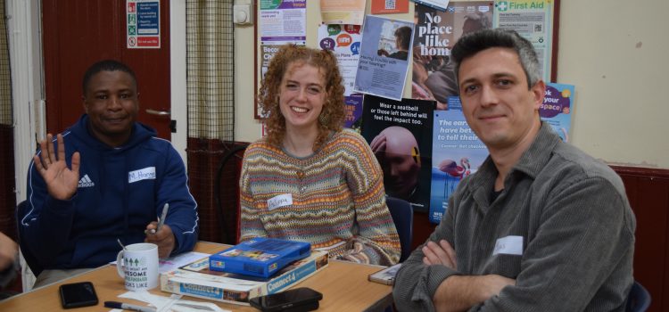 Three people sitting at a table and looking and smiling at the camera.