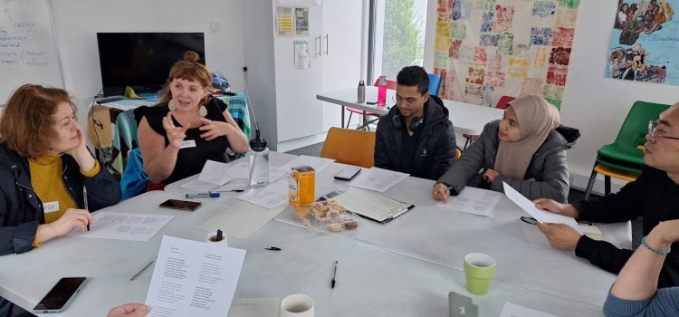 People in a classroom listening to the teacher as they write on paper