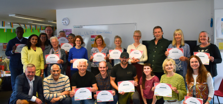 Volunteers’ Week 2025: Celebrating our volunteers! A group of people in a classroom holding up certificates and smiling.