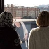 Two people looking outside a window at the Edinburgh skyline with their backs to the camera at the Welcoming Association main office.